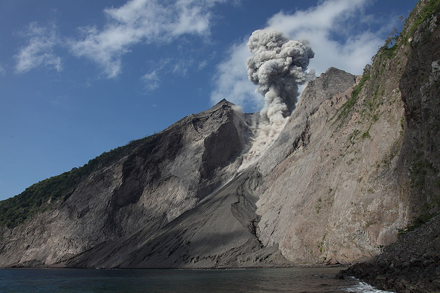 Sea and flank of Komba Island with eruption from active crater of Batu Tara volcano