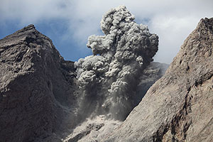 Explosive eruption producing dark grey ash cloud and volcanic bombs, Batu Tara volcano, Indonesia