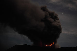 Dukono volcano at night with lightning in ash cloud