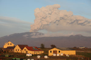 Eyjafjallajökull volcano. Farm with volcano erupting behind