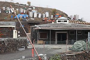 Main building of Wine Cooperative (Cha das Calderas) in Portelo with Salvaged barrels and equipment on hillside behind