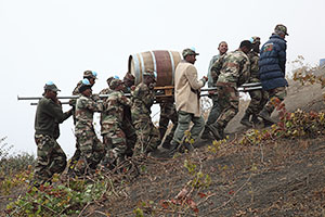 Soldiers climbing hill with wine barrel, Portela, Fogo Volcano Eruption, 2014