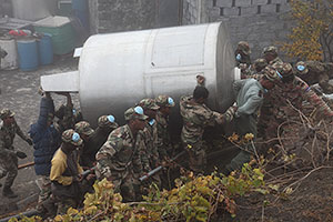 Soldiers carrying fermenter up hill during salvage operation from lava flows at Portelo, Fogo volcano