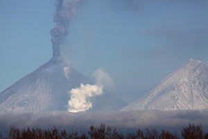 Ash from summit of Kliuchevskoi volcano and steam from melting glacier