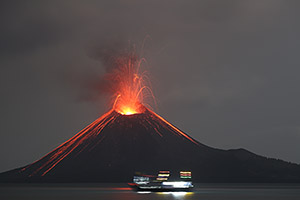 Fishing boat in front of erupting Anak Krakatau at night