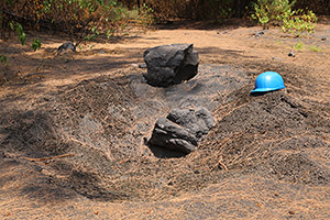 Volcanic Bomb impact crater on path, helmet for scale
