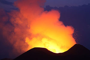 Nyamuragira Volcano eruption tree silhouettes with glowing crater behind